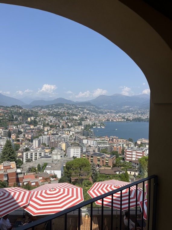 View over a lake and a city from a terrace with red-and-white umbrellas